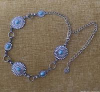 Full view of silver-tone concho chain belt showing medallions, rings, and extension chain