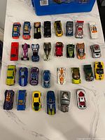 30 Hot Wheels cars arranged in rows on tabletop