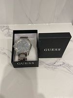 Watch in opened Guess box on marble surface