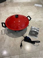 Electric wok assembled with lid, handles, power cord and booklet displayed