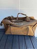 Front view showing Tracker logo, front zip pocket, handles and strap