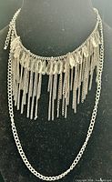 Full view of necklace on display form showing layered fringe, clear beads and lower curb chain