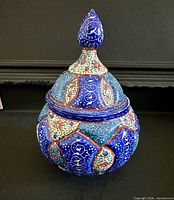 Front view of hand-painted enamel ceramic jar with lid in place