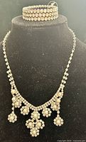 Necklace draped on bust with stretch rhinestone bracelet on top