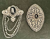 Front of both brooches showing design, cabochons and chain drapes
