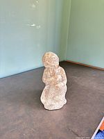 Front three-quarter view of plaster figurine showing child embracing dog