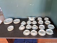 Full 57-piece set arranged on table: stacks of plates, cups with saucers, soup bowls with saucers, gravy boat and underplate