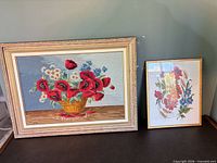 Both framed needlepoints side by side showing relative sizes and frames