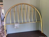 Full view of arched gold-tone metal headboard