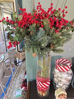 Tall vase with floral arrangement and adjacent ornament-filled glass vase