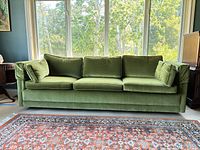 Front view of green velvet three-seat sofa with cushions attached