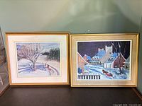 Both framed winter landscape paintings side by side