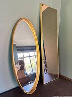 Both gold framed mirrors leaning against wall