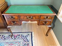 Full view of walnut writing desk with green leather top and drawers