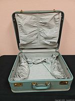 Suitcase open showing gray lining, straps and interior