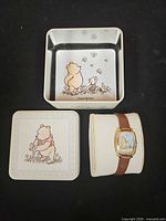 Watch on cushion inside tin base, lid nearby