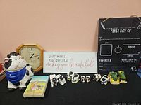 Lot overview showing cookie jar, clock, quote sign, cow figurines, tractors, books