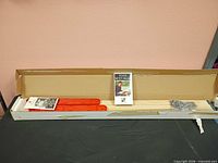 All kit components in opened box: plastic rails, dowels, hardware bag, manual