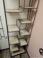 Front view of tall metal frame bookcase showing staggered wood shelves
