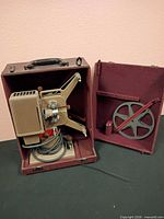 Projector secured inside open carrying case with reel holder in lid