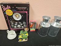 Group shot of boxed Barbie tea set, Kelly Club Belinda doll, John Deere shakers, galvanized milk cans, porcelain creamer