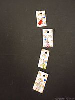 Four cards with multicolor enamel charm earrings
