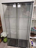 Front view of both glass display cabinets showing black metal trim and interior shelves