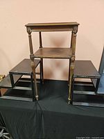One brown turned wood two-tier table standing on two black risers