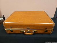 Front and top of closed suitcase showing exterior condition, handle and hardware
