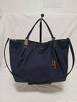 Front view of navy python-embossed Kate Spade satchel showing logo, handles, strap and hardware