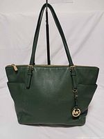 Front view of green Michael Kors Jet Set tote showing overall design, gold hardware and charm