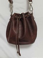 Front view of brown leather Roots bucket bag showing drawstring and texture