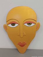 Front view of painted wooden face wall hanging