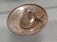 Front view of sterling sombrero brooch showing engraved floral motifs and rope edge
