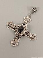 Front view of ornate sterling silver filigree cross pendant with onyx