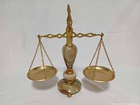 Front view of brass and onyx balance scale showing pans and column