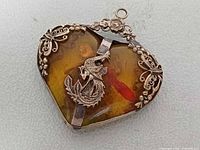 Front view showing amber cabochon, fish motif, filigree border
