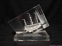 Full view of angled lucite block on base showing sailing ship carving