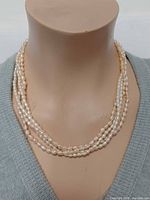 Necklace displayed on bust showing multi-strand design and pearl color