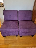 Front view of the two matching aubergine armless chairs side by side