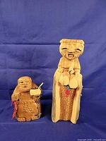 Front view of both carved figures showing size difference and accessory details