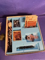 Tray with assorted beads, clasps, thread spool and tool