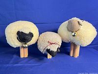 Front view of three woolly sheep figurines on blue backdrop