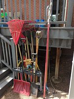 Full view of rack with long-handled rakes, shovels, pole pruner and saws