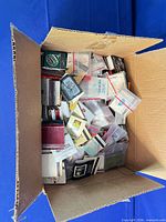 open cardboard box filled with numerous vintage matchbooks, some in plastic bags