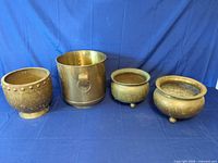 Front view of all four brass pots showing shapes and patina
