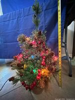 Artificial tabletop tree with tape measure showing height and multicolor lights