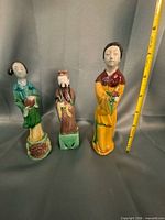 Three standing human figurines with tape for scale