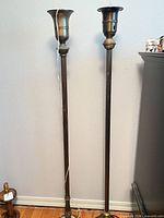 Full view of both brass torchiere floor lamps standing side by side