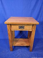Front view of one oak end table showing drawer and shelf